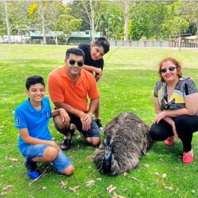 A man, woman and two boys pose on the grass next to a seated emu or ostrich at a wildlife park